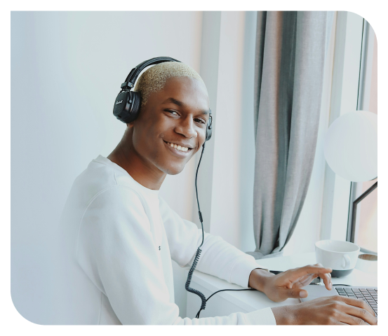 Jeune homme souriant portant un casque et travaillant sur un ordinateur, illustrant un freelance à la recherche d'un expert-comptable fiable, disponible et abordable