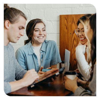 Groupe de personnes souriantes en réunion autour d'une table, symbolisant la collaboration et l'esprit d'équipe du cabinet d'expertise comptable Neovi