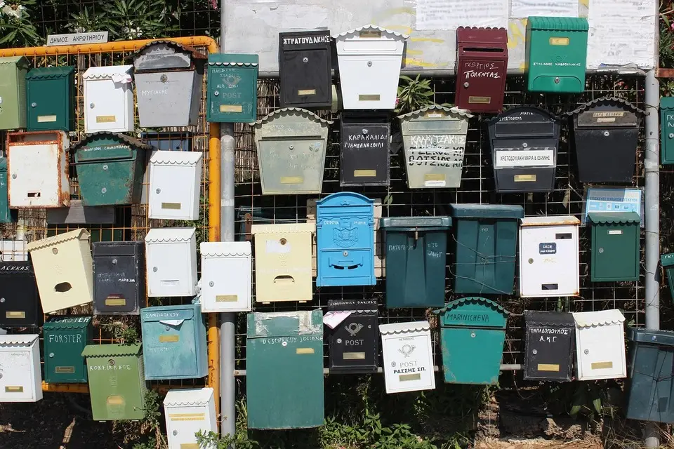 Un mur rempli de boîtes aux lettres variées, représentant la gestion d'adresses pour une activité professionnelle.