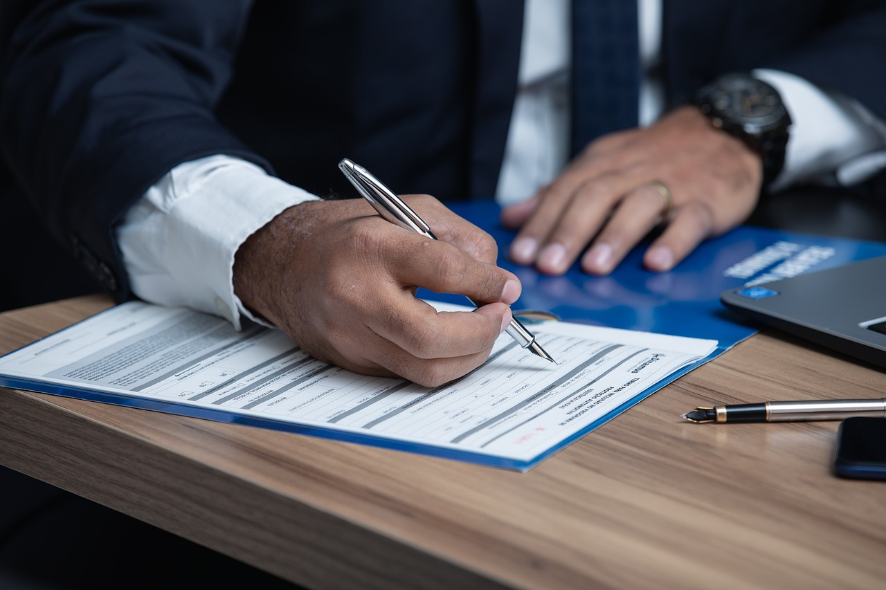 Un entrepreneur en costume signant un document sur un bureau en bois, symbolisant le choix entre une SASU et une EURL en 2025.