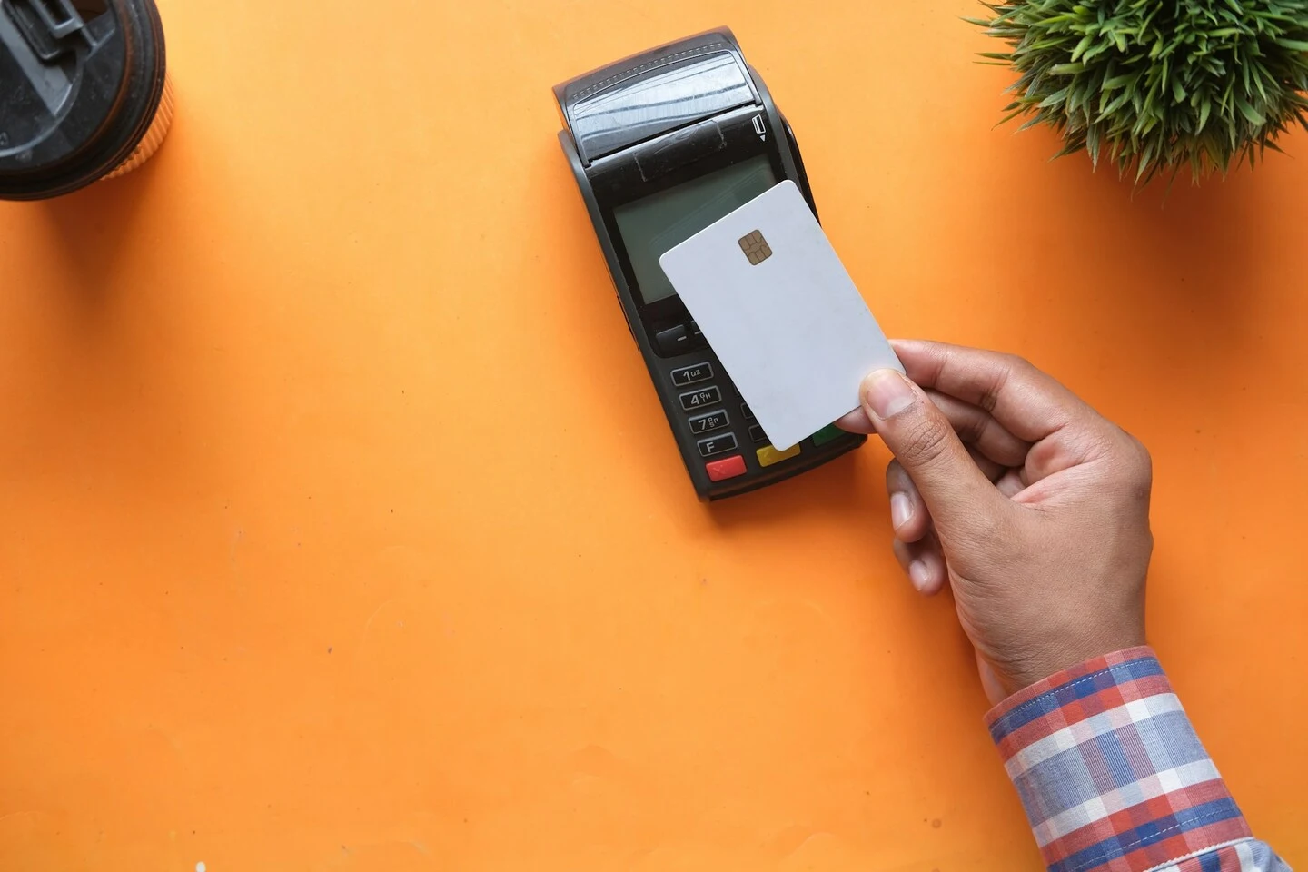 Une main tenant une carte bancaire devant un terminal de paiement, illustrant la gestion fiscale et les stratégies d’optimisation en SASU ou EURL.