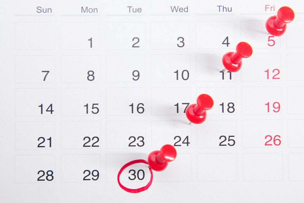 Calendrier avec des punaises rouges et une date encerclée, symbolisant les échéances fiscales importantes des freelances en 2025.