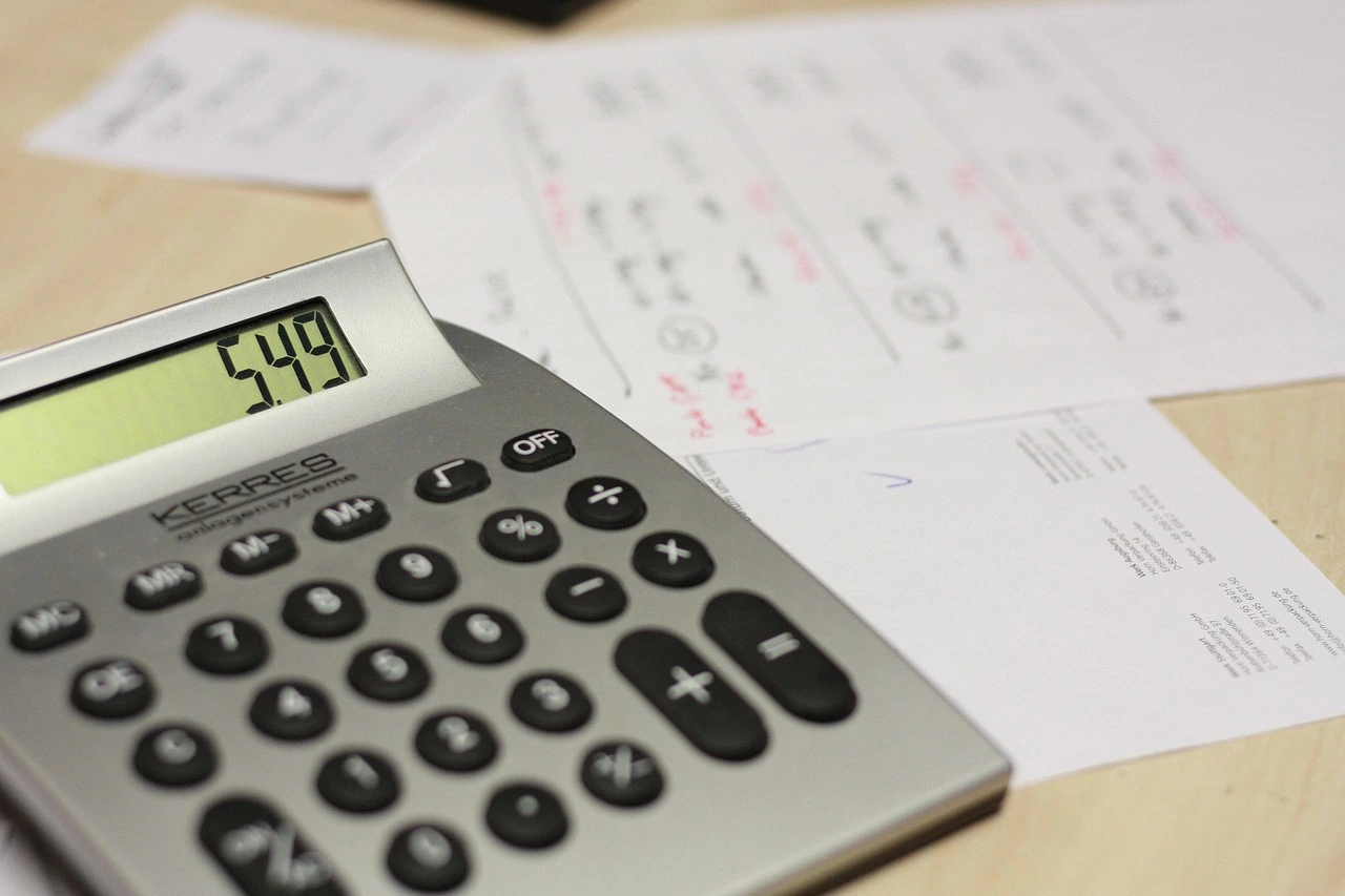 Calculatrice affichant un montant sur fond de documents administratifs.