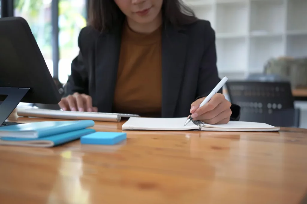 Freelance en train de prendre des notes face à une tablette, documents professionnels sur la table